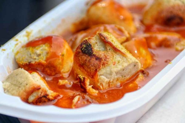 Traditional German currywurst served with rich curry ketchup sauce — sliced bratwurst covered in tangy, spiced tomato curry sauce, a classic street food from Berlin