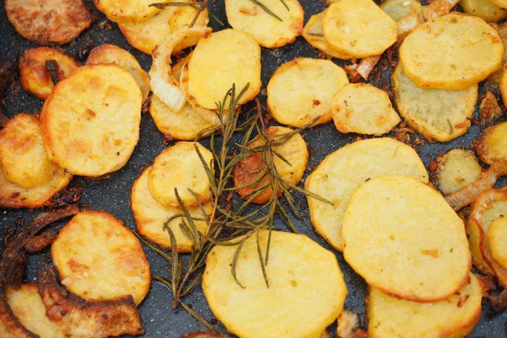 Golden bratkartoffeln potatoes pan-fried with onions and rosemary — traditional German fried potatoes compared to roasted potatoes in the UK
