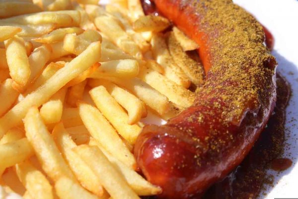 Authentic German currywurst topped with curry powder and sauce, served alongside crispy fries.