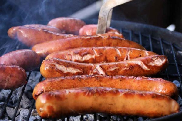 Authentic German frankfurters grilling over charcoal — showing the golden colour and natural casing that explain who makes the best frankfurter in the UK