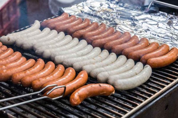German Bratwurst and Frankfurter sausages grilling on a BBQ for catering and events in the UK.