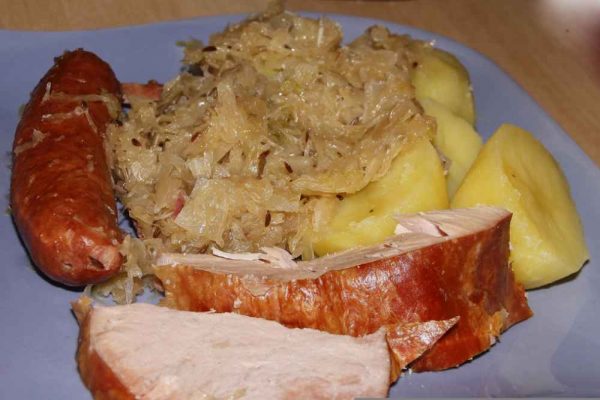 Traditional German sauerkraut served with smoked sausage, potatoes, and pork — a hearty dish loved by authentic German sausage suppliers and home cooks alike