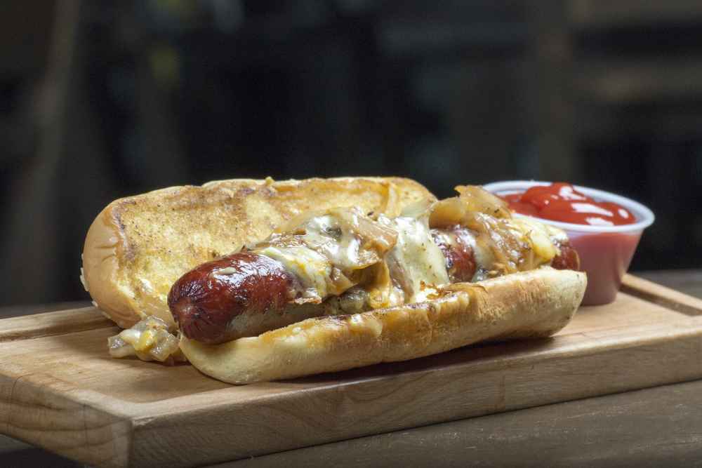 Bratwurst topped with caramelised onions and melted cheese in a toasted bun