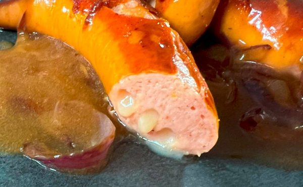 Close-up of a Käsekrainer, also known as a Cheese Frankfurter, showing the melted Emmental cheese inside the sausage after grilling.