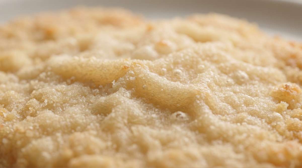 Extreme close-up of a light golden schnitzel crust with delicate ripples and airy blistering